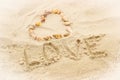 Word love written on sand at the beach, heart of shells Royalty Free Stock Photo