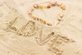 Word love written on sand at the beach, heart of shells Royalty Free Stock Photo