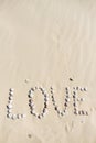 Word love written on the sand with sea shells at sunset on the beach Royalty Free Stock Photo