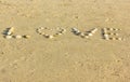 Love written with sea shells on sand at sunset Royalty Free Stock Photo