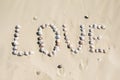 Word love written on the sand with sea shells at sunset on the beach Royalty Free Stock Photo