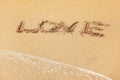 Word LOVE written in wet sand on the beach, sun shining over Royalty Free Stock Photo