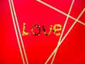 Word love of yellow,gold sparkling metal hearts reflecting light on red background with 5 five packaging golden ribbon