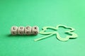 Word LUCK made with wooden cubes and paper clover leaf on background