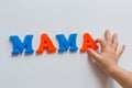 The word MAMA is made of colored magnetic letters typed by a child`s hand. Mother`s day.