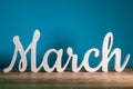 The word MARCH - wooden text at dark blue background. Spring concept