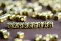 Word MARKETING made from small golden letters on the brown backg Royalty Free Stock Photo