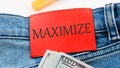 Word Maximize on the red leather label of jeans on a white background in a composition with American dollars Royalty Free Stock Photo