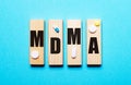 The word MDMA is written on wooden blocks on a blue background near the pills. Medical concept
