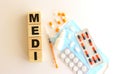 The word MEDI is made of wooden cubes on a white background. Medical concept