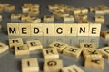 The word medicine, made of square wooden letters on a gray background