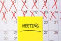 The word meeting written in black text on a yellow sticky note posted to a calendar page as a reminder. Close up of a personal Royalty Free Stock Photo