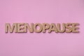 Word Menopause made of wooden letters on pink background, flat lay