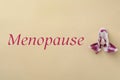 Word Menopause and orchid flower on beige background, top view