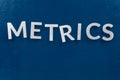 The word metrics laid with silver metal letters on classic blue surface - wtih careless dodging order