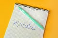 Word Mistake written with erasable pen in notepad on yellow background, above view