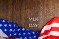 the word MLK day laid with silver metal letters on wooden surface with crumpled USA flag at lower side