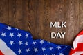 the word MLK day laid with silver metal letters on wooden surface with crumpled USA flag at lower side