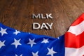 the word MLK day laid with silver metal letters on wooden surface with crumpled USA flag underneath