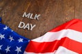 the word MLK day laid with silver metal letters on wooden surface with crumpled USA flag underneath