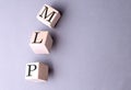 Word MLP on wooden block on the grey background Royalty Free Stock Photo