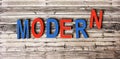 The word MODERN is composed of multicolored letters on a wooden background,