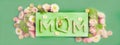 Word MOM and spring flowers on green background. Creative banner, Mothers day. Close-up. Generated AI