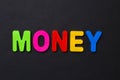 The word MONEY written in letters of the children`s magnetic alphabet on a black Royalty Free Stock Photo