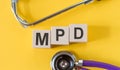 Word MPD - Multiple Personality Disorder, building from wooden cubes on yellow desk with stethoscope Royalty Free Stock Photo