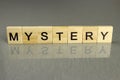 The word mystery is made up of square wooden letters on a gray background. Concept for mysteries, suspense and crime thriller