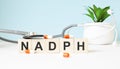 The word NADPH is written on wooden cubes near a stethoscope on a wooden background. Medical concept Royalty Free Stock Photo