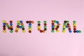 The word natural are contained by colored candies on a pink background Royalty Free Stock Photo
