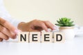 the word need, spelt on wooden cubes with letters over a white background Royalty Free Stock Photo