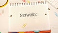 The word NETWORK is written on a white notepad with a grid pattern. The notepad is surrounded by paper clips, push pins, and a Royalty Free Stock Photo