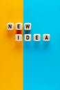 The word new idea written on wooden cubes on yellow and blue background. Finding and implementing new ideas