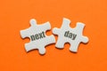 The word next day on two matching puzzle on orange background