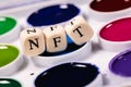 The word NFT is laid out of cubes with letters on background watercolors