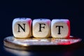 The word NFT is laid out of cubes with letters on golden cryptocoin