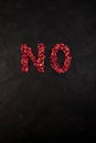 The word NO made of dried petals of scarlet roses. Dark background, copy space. Design element. Blank for poster or banner