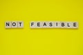 Word not feasible. Top view of wooden blocks with letters on yellow surface