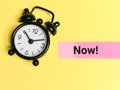 Word now on sticky note with alarm clock. Self reminder and motivation concept. Royalty Free Stock Photo