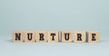 The word NURTURE made from wooden cubes on blue background