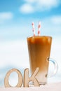 word OK with iced coffee latte on a beach ocean Royalty Free Stock Photo