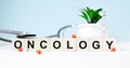 The word ONCOLOGY is written on wooden cubes near a stethoscope on a wooden background. Medical concept