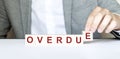 Word OVERDUE made with wood building blocks and business man in suit Royalty Free Stock Photo