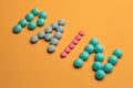 Word pain on orange background written with colorful pills. Painkiller tablets taken by prescription