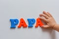 The word PAPA is made of colored magnetic letters typed by a child`s hand.