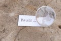 The word pause in English and a glass globe lie on a stone