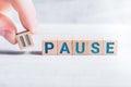 The Word Pause Formed By Wooden Blocks And Arranged By Male Fingers On A White Table Royalty Free Stock Photo