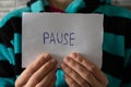 The word pause is written on a piece of paper that the quarantined girl is holding